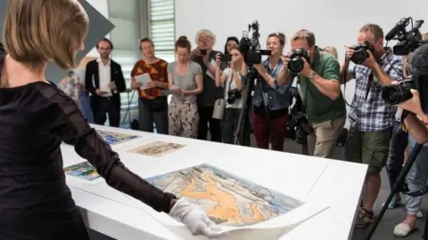 AFP An official displays artwork during a press preview of the first masterpieces of the estate of Cornelius Gurlitt at the Museum of Fine Arts Bern (07 July 2017)