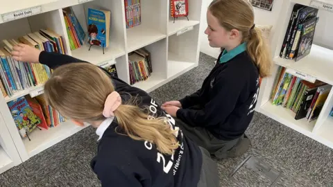 Two students looking at books in the fuselage library