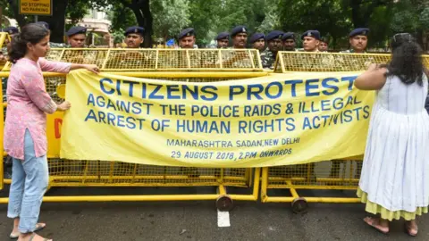 Getty Images Delhi Police personnel stand on duty as people stage a protest against the arrest of five activists