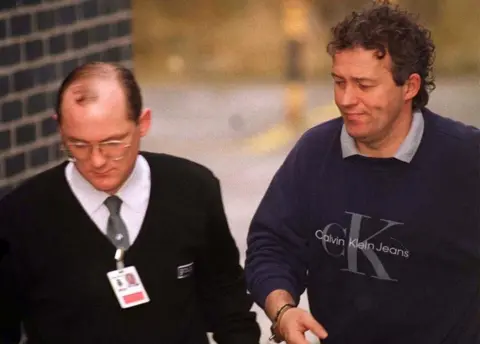 PA Barry Bennell, handcuffed to a custody officer, in 1998