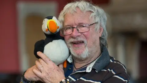 Bill Oddie holding a toy puffin