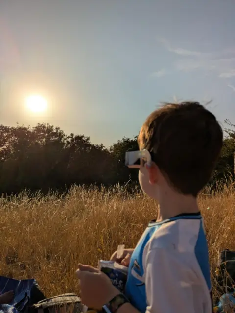 Boy wearing eclipse glasses looking at eclipse