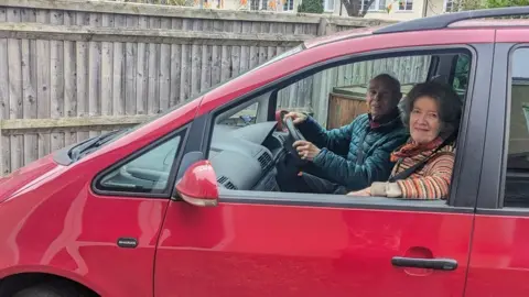 Richard and Helen Dodd Richard and Helen Dodd sitting in the front seats of their red people carrier. Mr Dodd in  a blue padded anorak is at the wheel and Mrs Dodd in a striped jumper is resting her arm on the open passenger window 