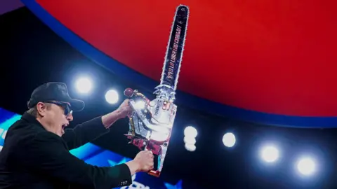 Reuters Elon Musk holds up a chainsaw onstage during the Conservative Political Action Conference (CPAC) in National Harbor, Maryland, on 20 February 2025