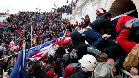 Reuters Kerumunan pendukung Trump yang mengelilingi gedung Capitol AS mengibarkan bendera dan mengacungkan tinju