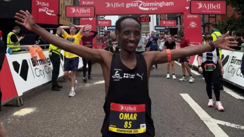 Great Birmingham Run A man with his arms out after finishing the race