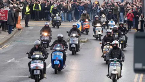 PA Fans on scooters lead the cortege following the funeral service of former Stone Roses and Primal Scream bass player Gary Mounfield, who was known as Mani, at Manchester Cathedral, following his death at the age of 63.