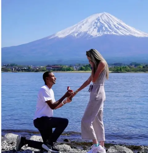 Instagram Michael Rimmer - wearing a white T-shirt and dark jeans - on one knee proposing to Eilish McColgan, who is holding a hand to her mouth in shock