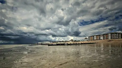 Joanna Kaczorowska A beach with dark clouds over 