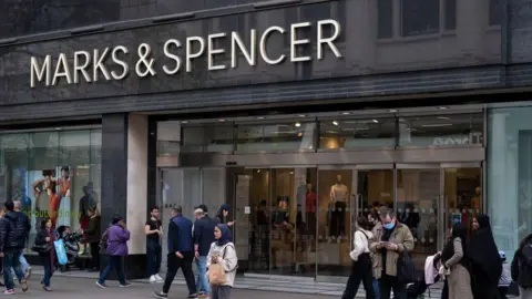 People standing outside and walking past at a M&S store in London