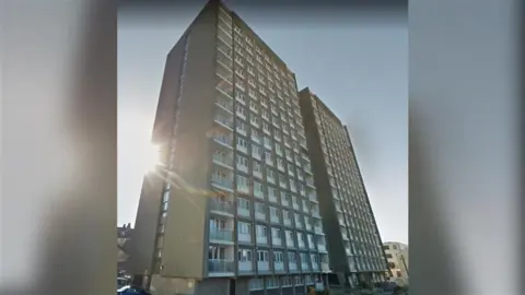 Two beige and white tower block buildings side-by-side.