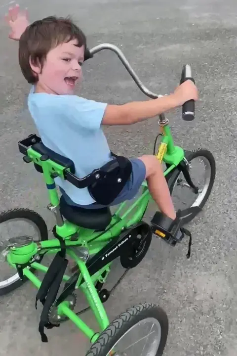 Tammy McDaid Tate is looking back and smiling while riding a tricycle.