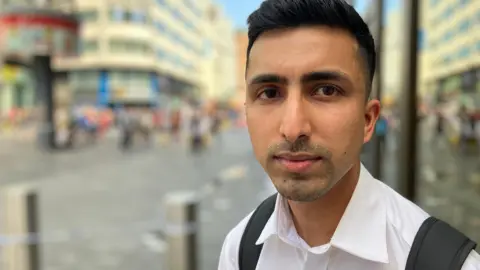 Abdullah, a young man with dark hair, black backpack and white shirt