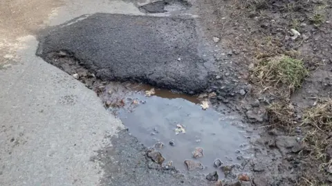 A deep, water-filled pothole