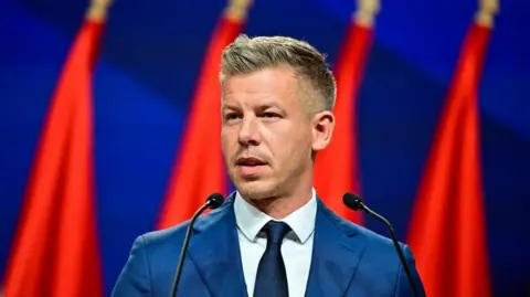 Reuters A man in a blue suit in front of a colourful blue and red background