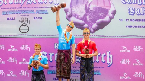 Rip Curl Lukas Skinner on the winners podium holding a trophy aloft