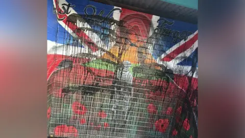 A mural of the union jack, poppies and a soldier have been ruined by black paint which has been thrown across it