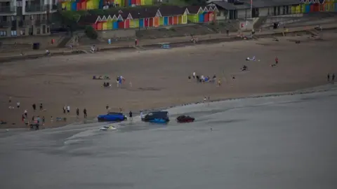 Alec Scott Two vehicles in the sea with jet skis alongside them