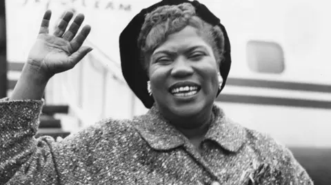 La cantante de gospel y guitarrista estadounidense Sister Rosetta Tharpe (1915-1973) saluda al llegar al aeropuerto de Londres, el 21 de noviembre de 1957.