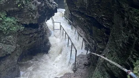 A pathway with metal handrails has been submerged under water. 