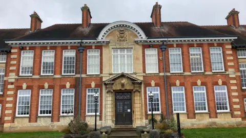 Laura Coffey/BBC A two storey brick building with lots of white framed bay windows.