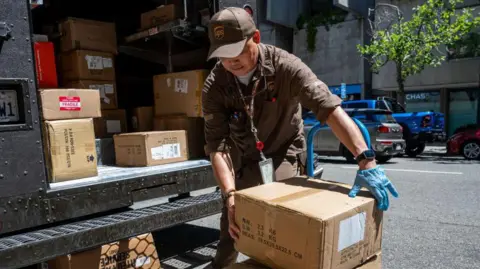 A UPS delivery driver loads parcels on to a trolley. 