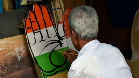 Getty Images A man hand paints the election symbol of the Indian National Congress political party in West Bengal's capital Kolkata (previously called Calcutta) on 5 April 2026. The symbol is the cutout of a palm facing outward. It is coloured saffron at the top, white in the middle and green in the bottom - resembling the Indian flag.