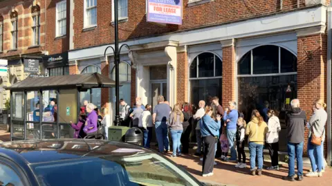 A queue of people outside a shop.