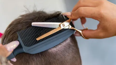 Stock photo of stylist giving a precise haircut with focus on the details 