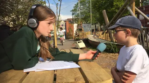 EASTSIDE COMMUNITY TRUST Two children sat at a picnic bench recording a podcast