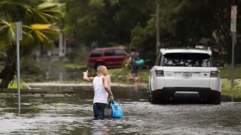 AFP Man wades through flooded street in Florida