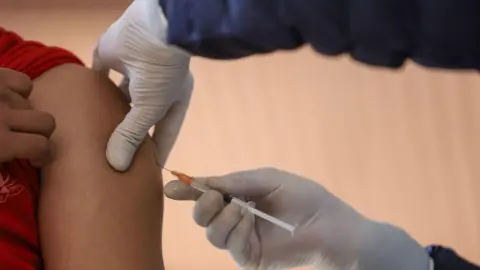 Getty Images Medical professional puts needle into someone's arm