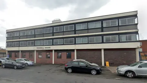 Google The exterior of Windmill House which is a two storey black and white building.