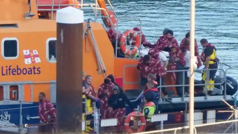 GARETH FULLER/PA WIRE A group of people believed to be migrants are taken from the RNLI lifeboat to Dover in Kent on Saturday