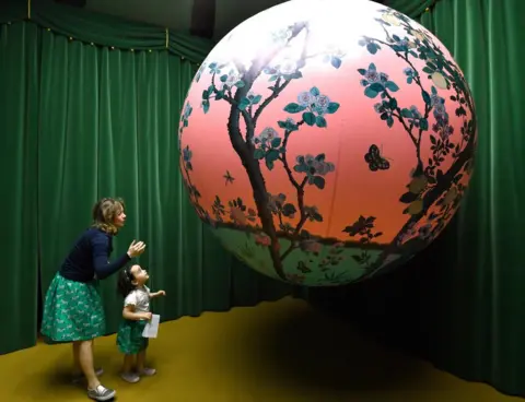 Daniel Del Zennaro / EPA A woman and a young girl look at a a painted globe