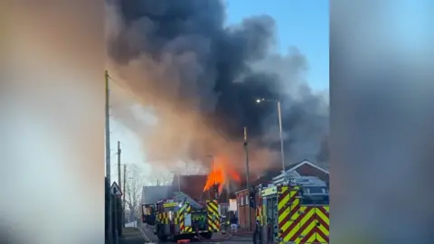 Smoke and flames rise into the air from a building fire.