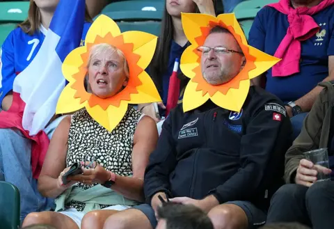 Getty Images Two Welsh fans watch the match wearing paper daffodils hats