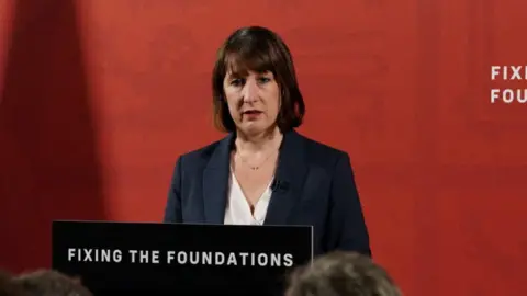 Reuters Chancellor of the Exchequer Rachel Reeves speaks during a press conference at a lectern with the slogan "fixing the foundations"