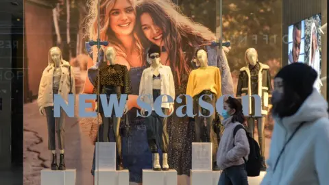 Getty Images people wearing masks walk past a Topshop shop window