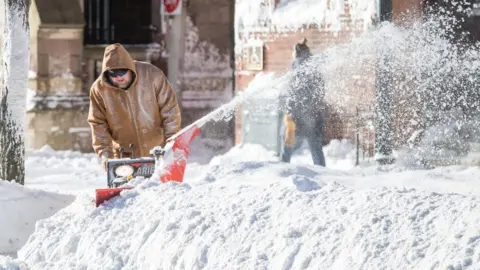 Getty Images A man clears snow away from his home in Boston