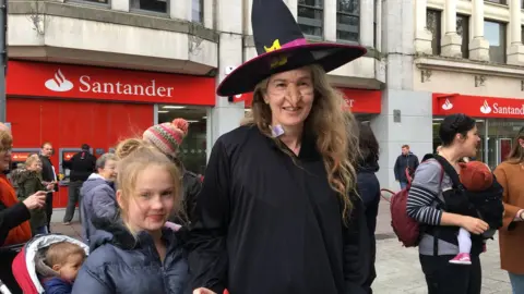 A photo of a woman dressed as a witch with her children