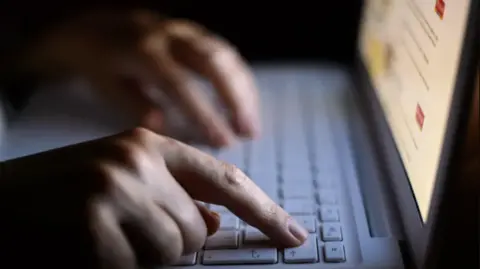 A close up of hands typing on a laptop keyboard.