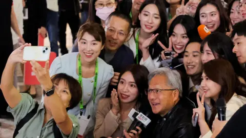 Reuters Nvidia CEO Jensen Huang poses for a selfie with members of the media at COMPUTEX forum in Taipei.