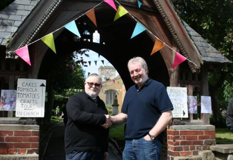 Rev David Brooke and Ken Wilson shake hands in front of St Cuthbert's Church