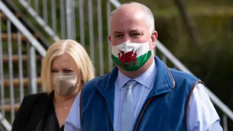 Getty Images Leader of the Welsh Conservative Group in the Senedd Andrew RT Davies and his wife, Julia, arrive to cast their vote at a polling station at Llancarfan Village Hall on May 6, 2021 in Llancarfan, Wales