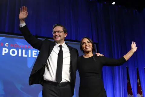 Getty Images Pemimpin Partai Konservatif Kanada yang baru terpilih Pierre Poilievre (kiri) dan istrinya Anaida melambai kepada para pendukungnya selama Konvensi Partai Konservatif di Shaw Centre, Ottawa, Kanada pada 10 September 2022.