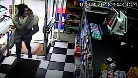 Sussex Police CCTV image of a dark haired woman walking into a shop.