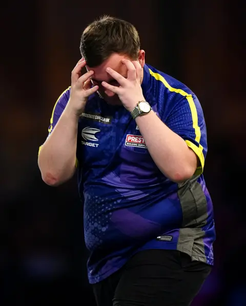 PA Media Luke Littler grabs his face