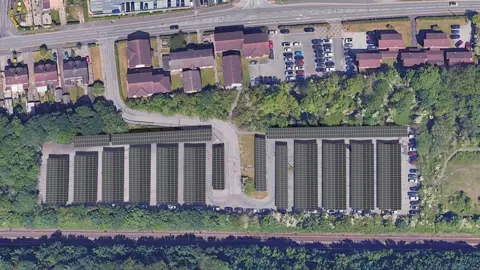 An aerial artist's impression of the new solar carports showing rows of panels surrounded by a railway line and trees 