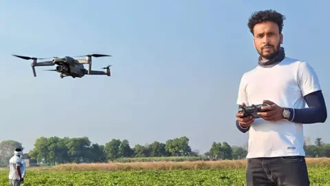 Vishal Jaiswal holding a drone controller, with a drone flying near him.